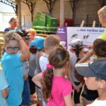 Enfants et éleveuse devant panneau pédagogique