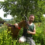 Eleveur et chèvre dans champs, bien être animal