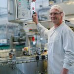 Homme technicien devant machine, chaine de yaourts
