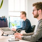 Deux jeunes devant ordinateurs, bureau
