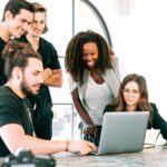 Groupe de jeunes regardant ordinateur, formation, rire, bureau