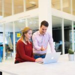 Homme et femme devant un ordinateur, debout, loft, bureau, travail réunion, Mac